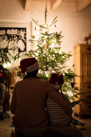 Two people sitting in front of a Christmas tree. Photo Credit: Unsplash