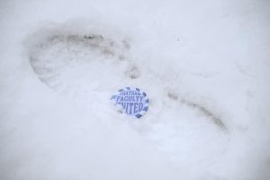 A faculty union pin sits in the snow.