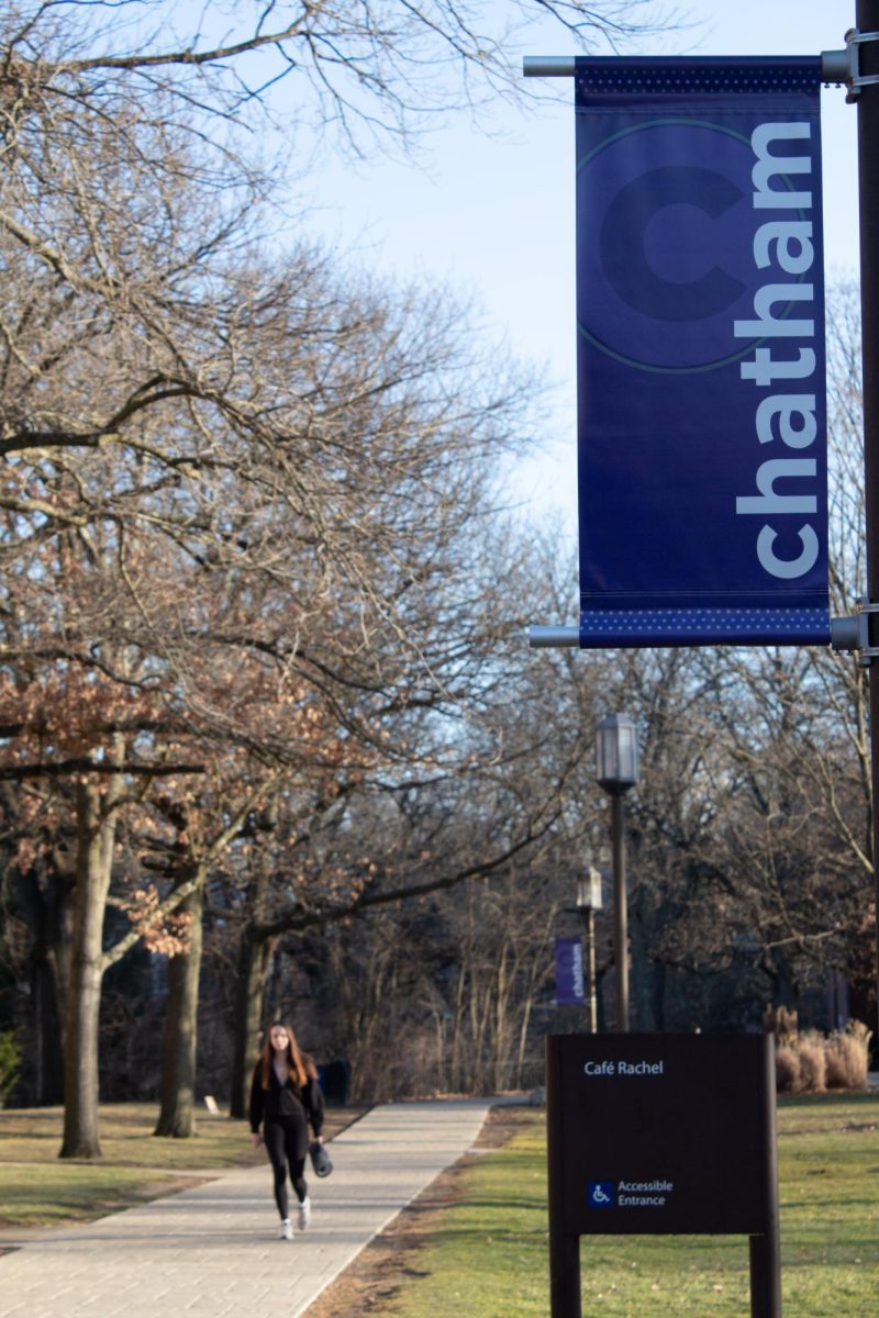 Student walks by Chatham University sign at the Shadyside campus