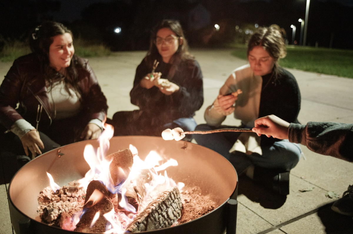 Students enjoy the warmth of the bonfire while cooking marshmallows during Fall Fest on Oct. 12.