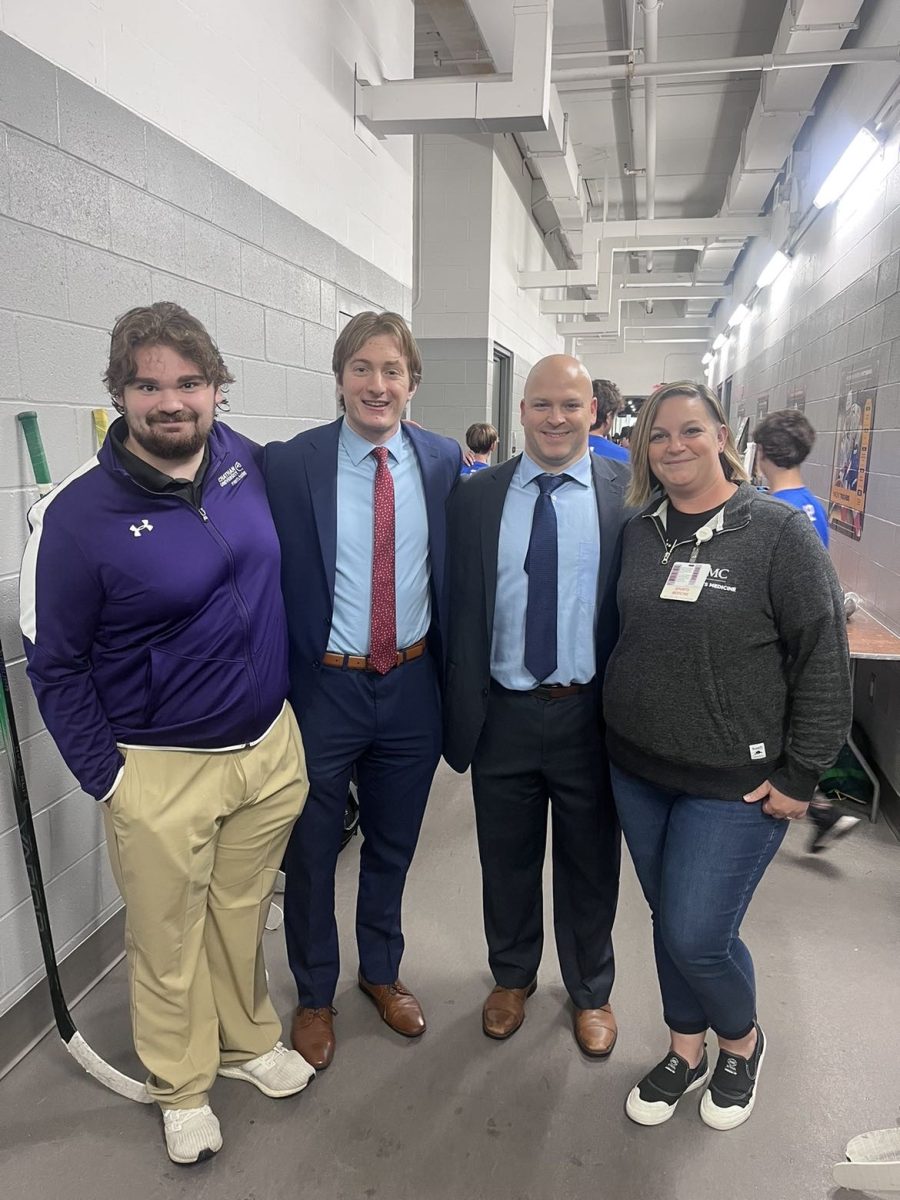 Men's ice hockey equipment manager Ryan Preston '25, Ryan Miller '25, head coach Michael Gershon and athletic trainer Rebecca Kayda pose for picture at UPMC Lemieux Sports Complex. Photo courtesy of Ryan Miller.