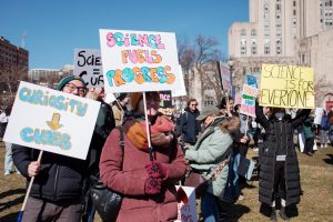 Students hold signs supporting scientific research. 